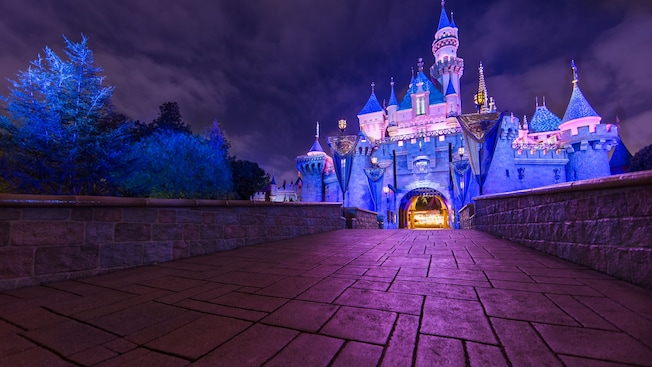 Un camino de piedra lleva al Sleeping Beauty Castle, iluminado durante la noche
