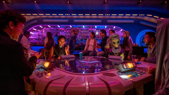 Various Guests play games and interact with Characters from foreign planets in a lounge aboard the Halcyon starcruiser