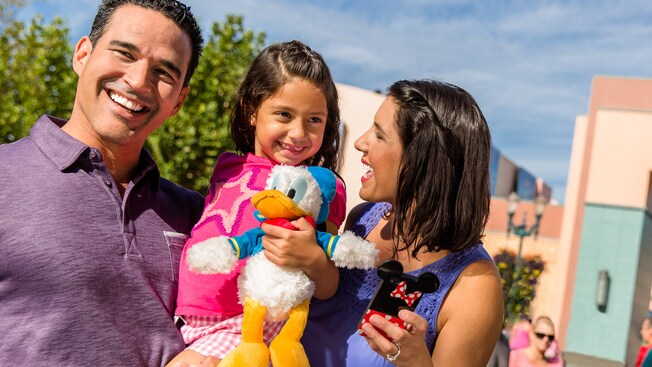 A man, woman and their daughter smiling as they enjoy Disney’s Hollywood Studios