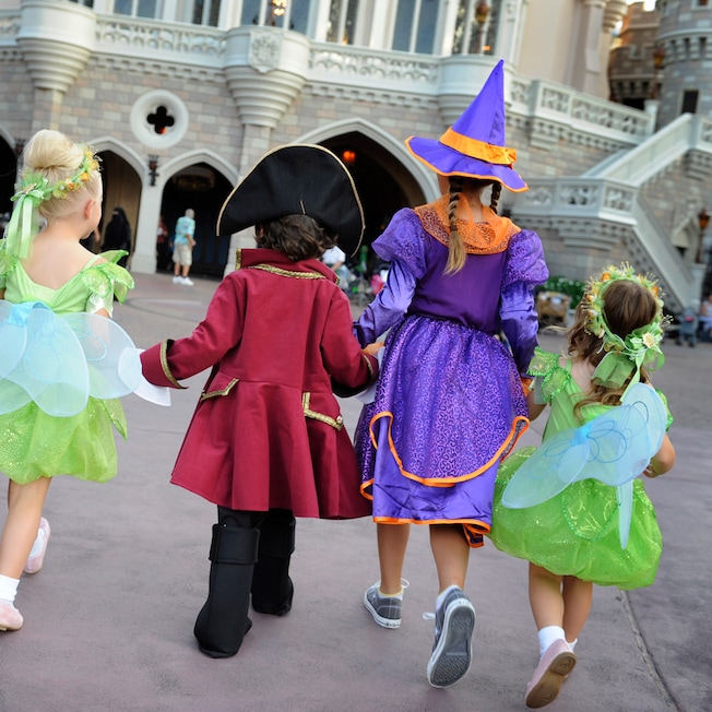 Five costumed children hold hands as they approach Cinderella Castle, including two witches, two fairies and a pirate