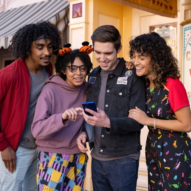 4 Guests using Disney Magic Mobile on their phone in Magic Kingdom park
