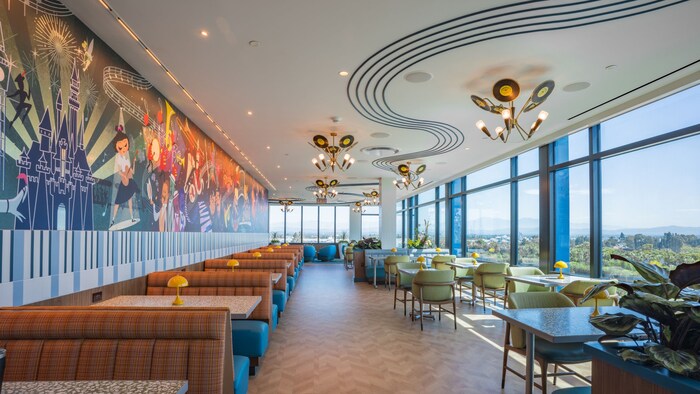 The dining area at High Key Club at the Disneyland Hotel with a music themed mural and large windows overlooking the Disneyland Resort