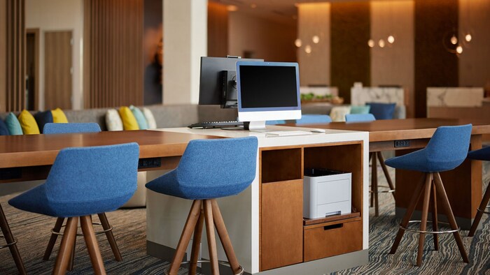 A modern business center with seating areas, desks and computers.