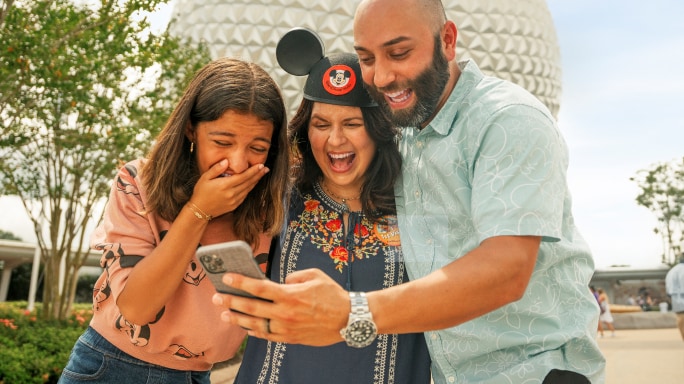 A family laughing as they view a photo on their phone