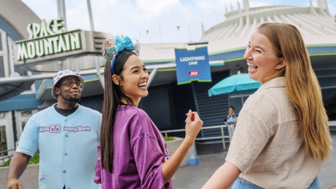 Three young people laughing outside the entrance to Space Mountain