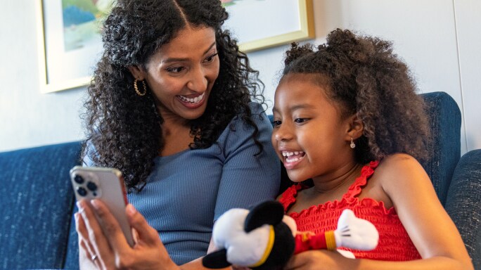 A mom holding her phone up for her daughter