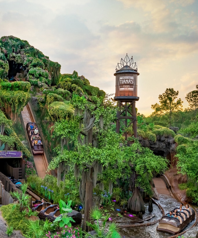 A boat full of Guests plunges down the water slide of Tiana's Bayou Adventure attraction