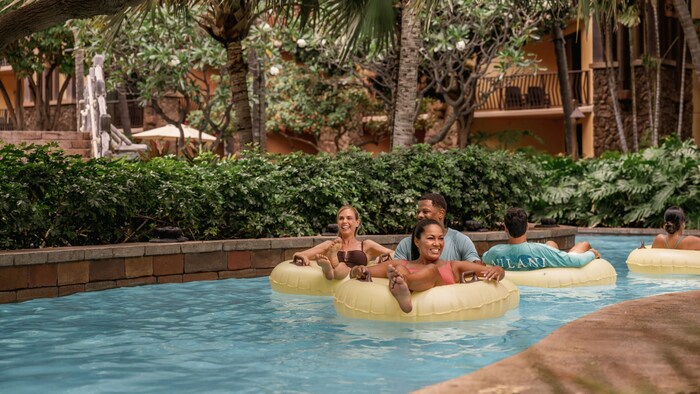 Guests sitting in inner tubes while floating through a lazy river at Aulani, A Disney Resort & Spa