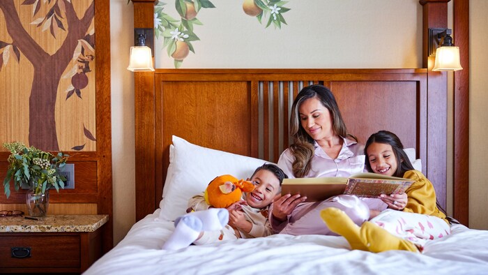 A mother reads a bedtime story to her kids in a Disneyland Resort hotel room