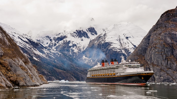 Un navire de Disney Cruise Line émerge d’une vallée aux montagnes enneigées