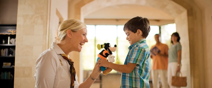 A woman gives a little boy a plush Goofy