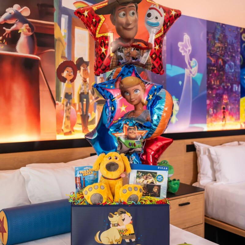 A gift box featuring Pixar themed toys and balloons