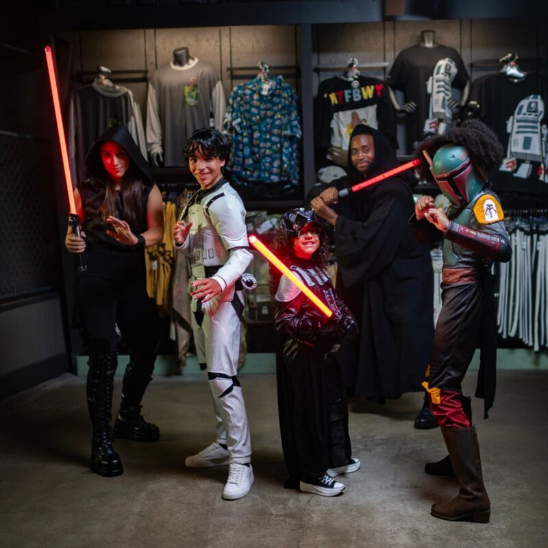 Un grupo de niños posa con sables de luz en Star Wars Trading Post en Disney Springs 