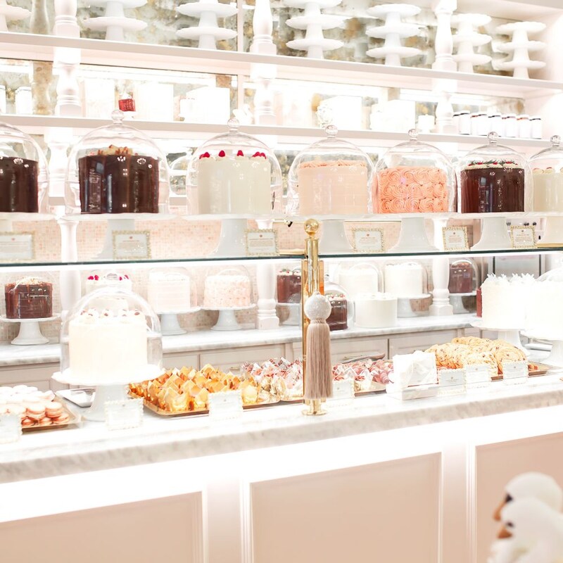 A dessert counter with cakes in glass cases and various desserts on trays