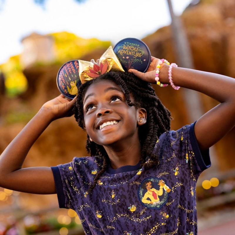 Una niña tirando de las orejas de su diadema de Minnie Mouse con temática de la princesa Tiana
