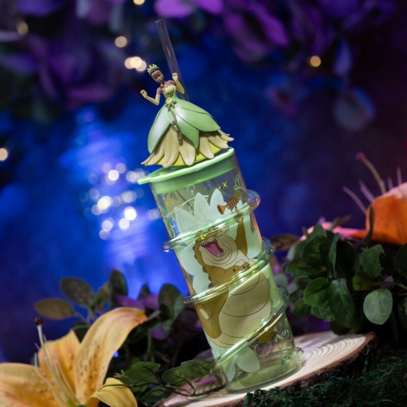 Um copo da Princesa Tiana com canudo em espiral, uma ilustração do jacaré Louis e uma bonequinha da Princesa Tiana em cima