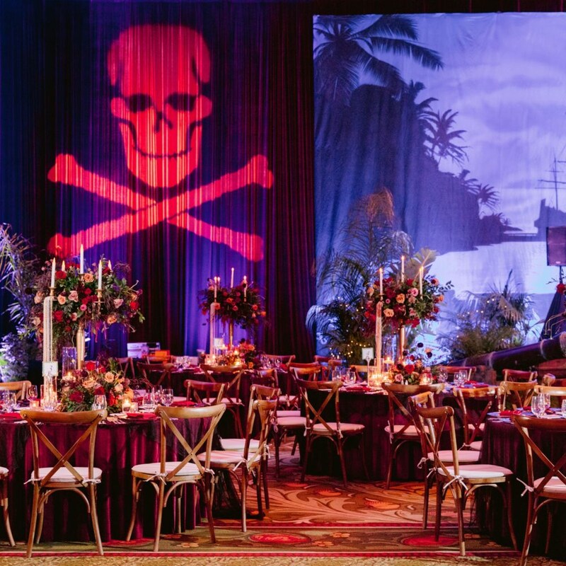 Dining tables with floral arrangements at a Pirates of the Caribbean themed event