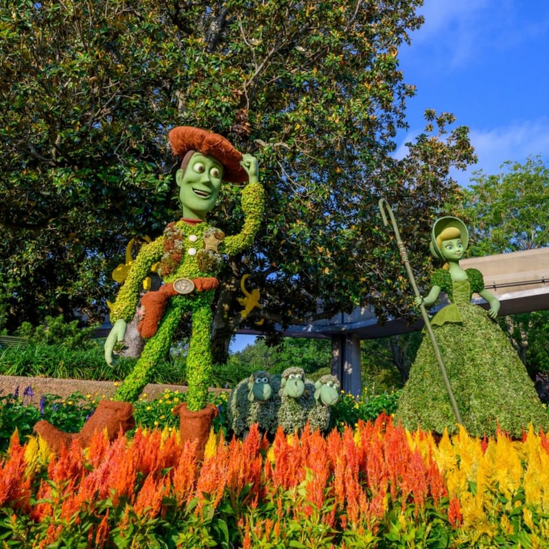 A garden with 3 topiaries featuring Woody, Bo Peep, Billy, Goat and Gruff from ′Toy Story′ near the monorail