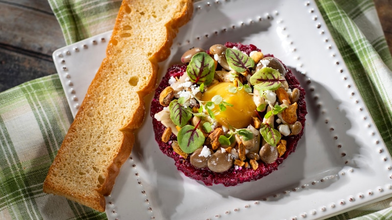 Citrus Braised Beet Tartare topped with pistachio pieces, crumbled cheese, fresh herbs and served with a slice of focaccia bread