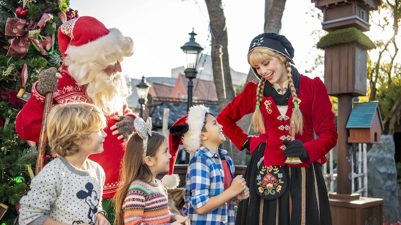 Three children smiling with 2 holiday storytellers at EPCOT