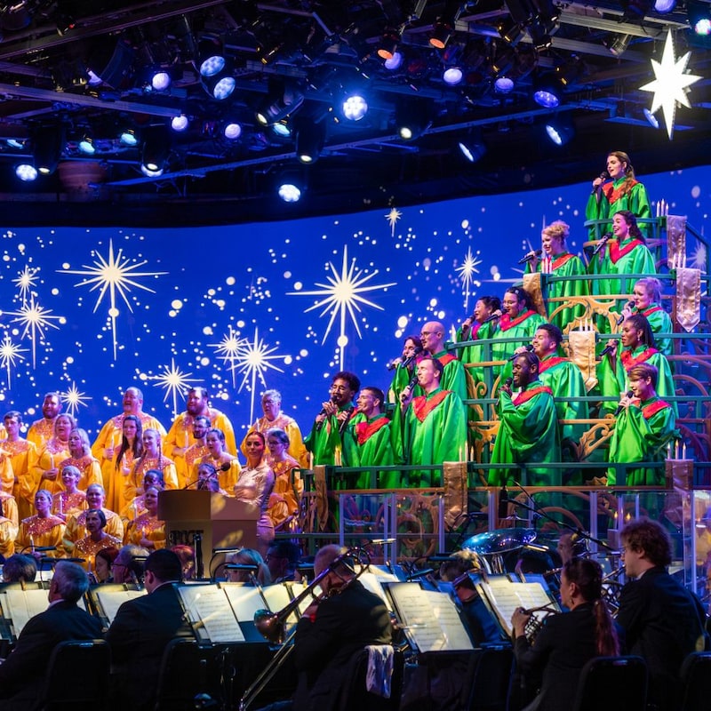Singers in holiday themed attire and an orchestra performing in the Candlelight Processional at Epcot