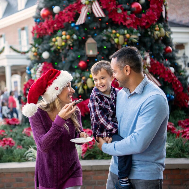A happy family of 3 and a huge Christmas tree during Holidays at Walt Disney World Resort