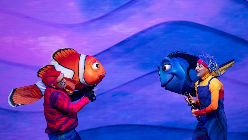 Dos miembros del elenco sostienen marionetas de Nemo y Dory durante una escena del espectáculo escénico Finding Nemo: The Big Blue… and Beyond!