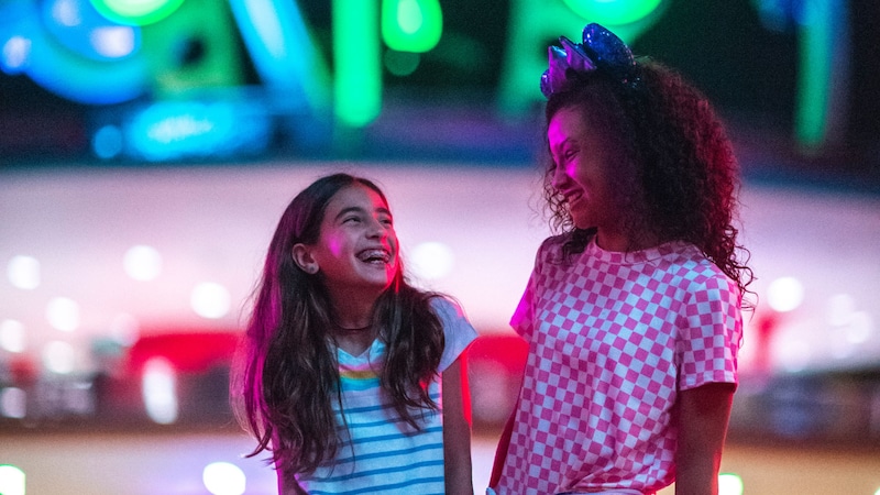 Dos niñas sonríen frente a Astro Orbiter en Tomorrowland, en Magic Kingdom Park
