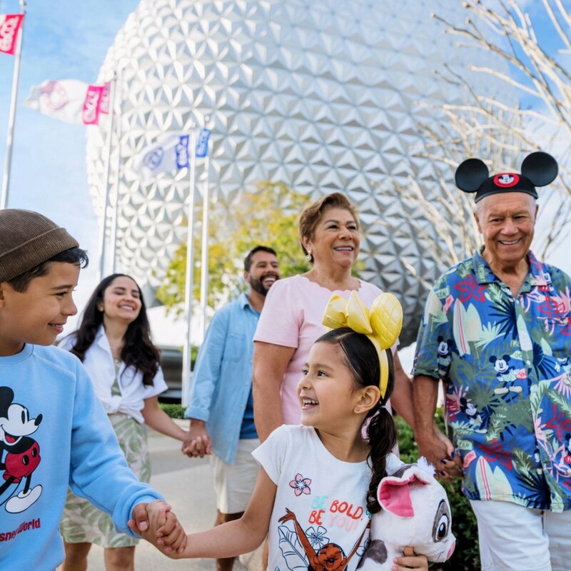Una familia multigeneracional caminando frente a Spaceship Earth en EPCOT