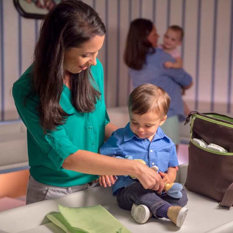 A woman tends to a toddler atop a changing table at the Baby Care Station in Magic Kingdom park