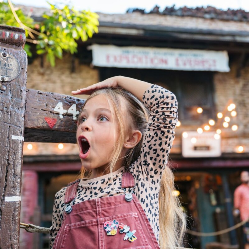 A young girl expresses shock and excitement as she clears the 44 inch height requirement at an attraction’s measuring station