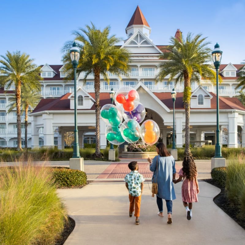 Une femme tenant des ballons Mickey marche avec sa fille et son fils à l’entrée du Disney’s Grand Floridian Resort and Spa