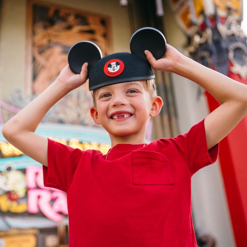A smiling boy wearing a Mickey Mouse ear hat while standing in front of Grauman's Chinese Theatre.