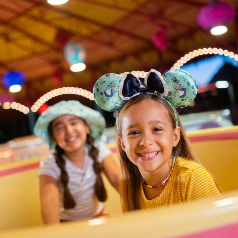 Deux jeunes filles souriantes assises dans une tasse de thé à l’attraction Mad Tea Party