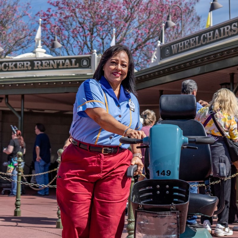 A smiling Cast Member brings out an ECV in front of the stroller shop.