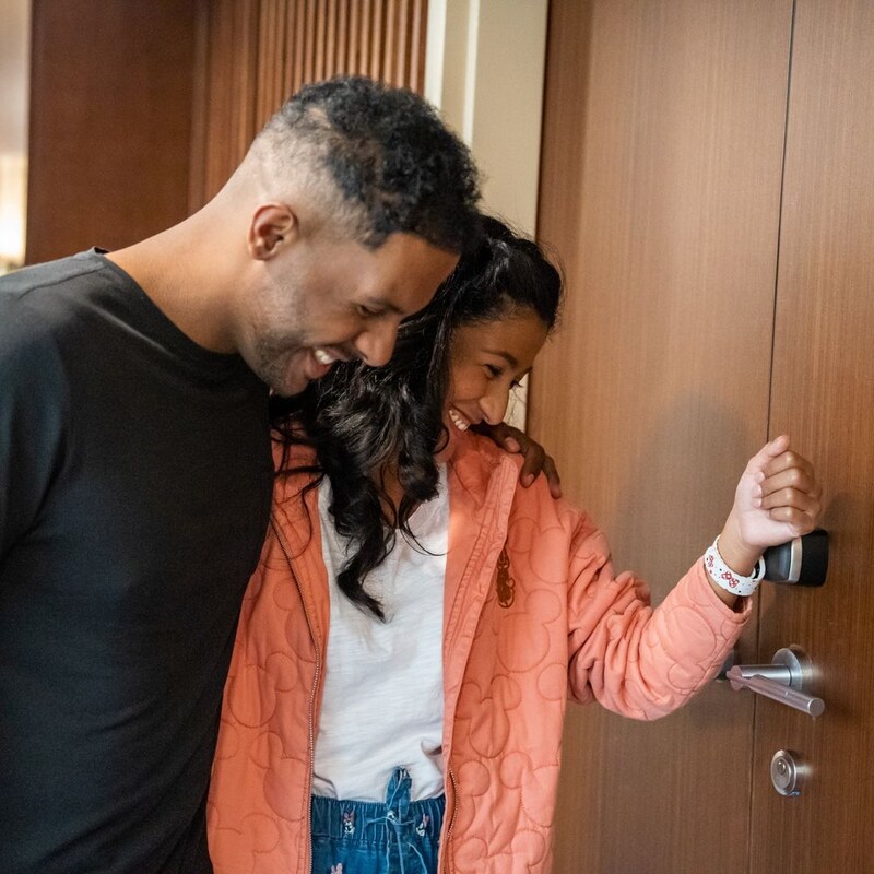 A couple uses a Disney band to unlock their hotel room door