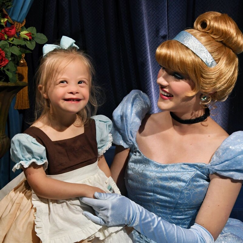 Cinderella holding a young girl on her knee