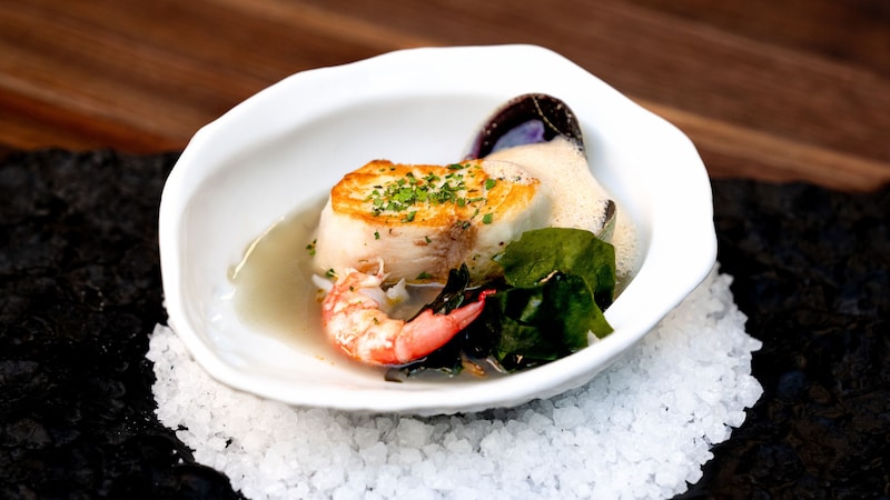 A bowl of Tide Pools with hiramasa and shrimp in a cockle broth and Uni foam