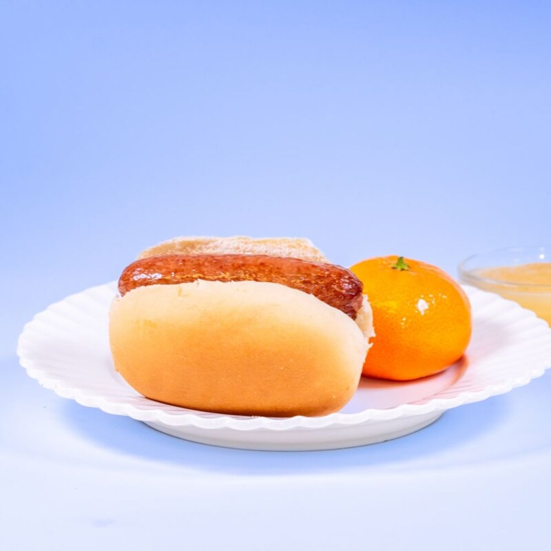 Hot dog on a bun served with a clementine and apple sauce, available during Bluey's Best Day Ever