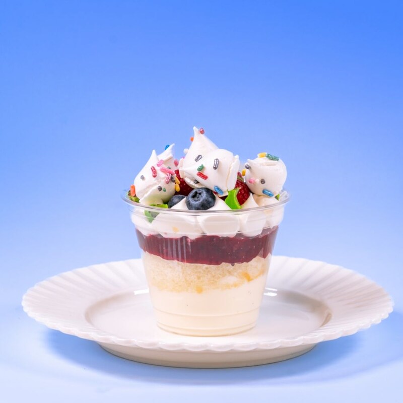 A layered dessert cup with berries, whipped cream and sprinkles, available during Bluey's Best Day Ever