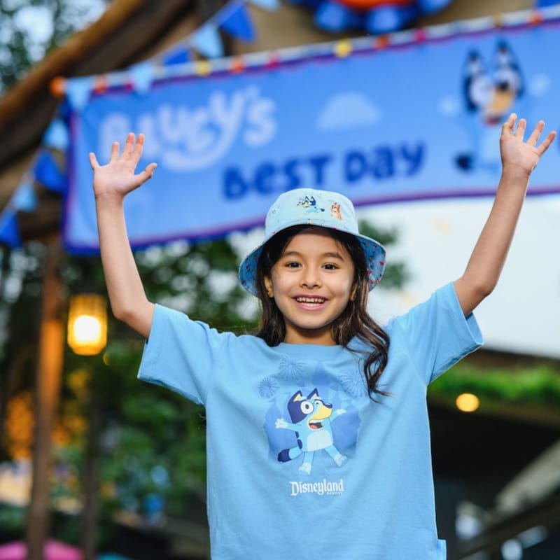 A young girl wearing a Bluey bucket hat and Disneyland Resort Bluey tee