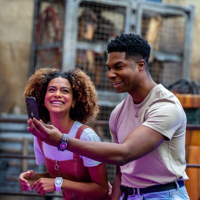 Two Guests wearing Disney bands share a laugh over content on a mobile device