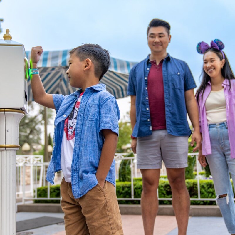 A child tapping a Magic Band Plus to a Lightning Lane entry touchpoint