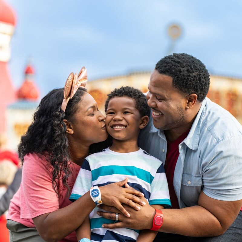 2 parents wearing Magic Bands and embracing a child