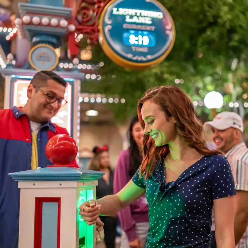 A woman tapping the Magic Band Plus on her wrist to a Lightning Lane entry touchpoint
