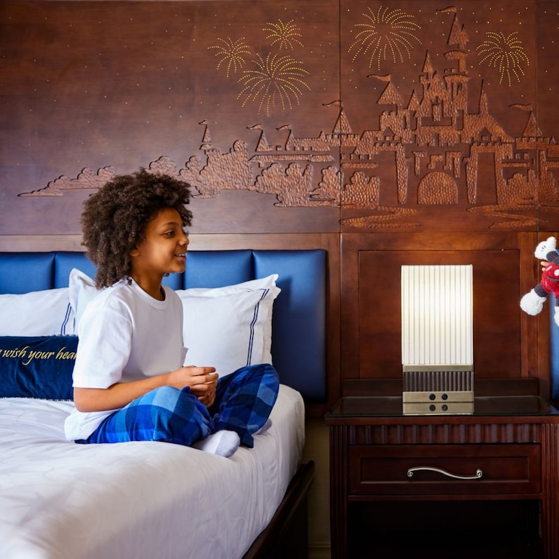 2 children playing with a Mickey Mouse plush in a Disney-themed hotel room