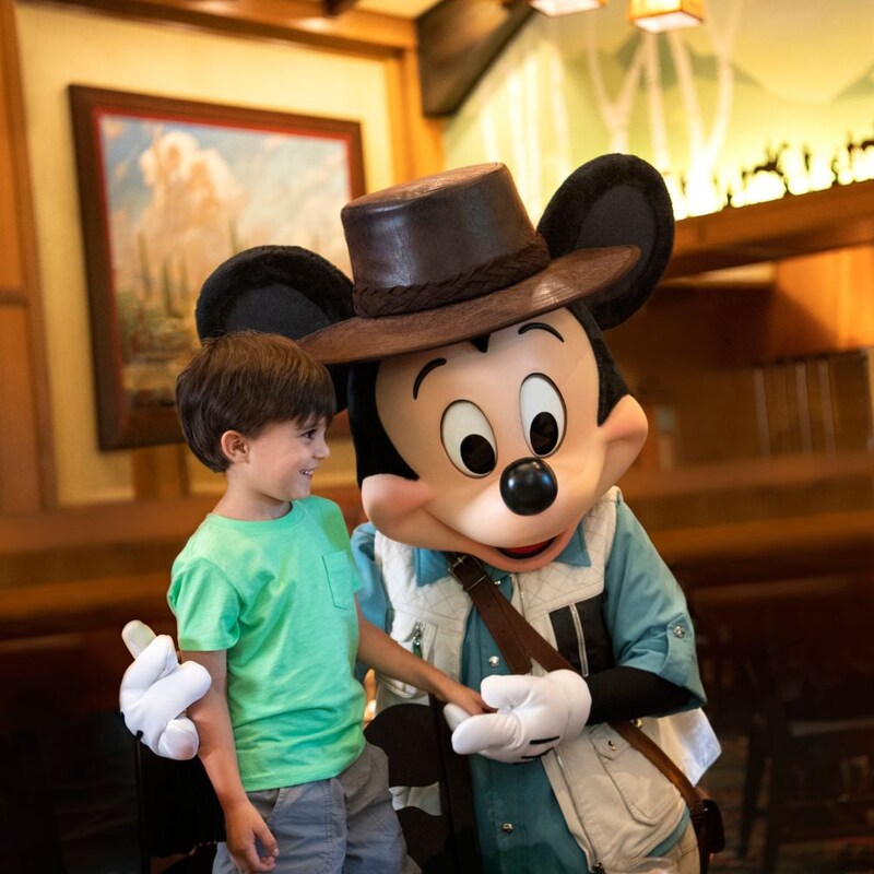 A child interacts with Mickey Mouse and Minnie Mouse