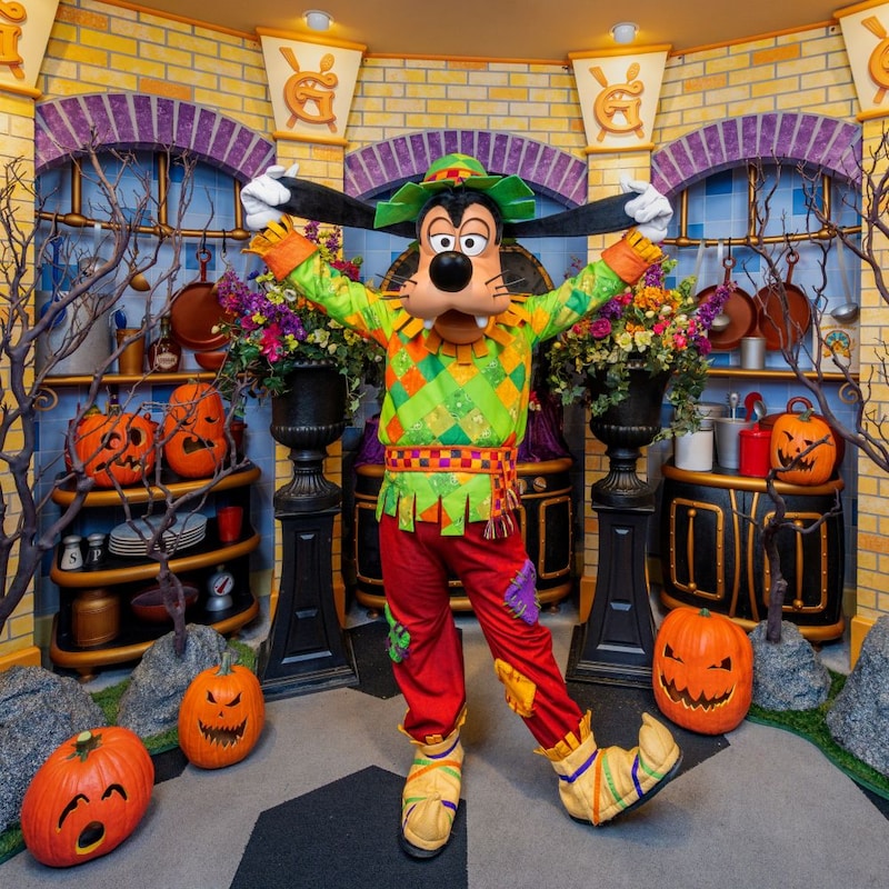 Goofy in a Halloween costume surrounded by jack o lanterns and spooky decor