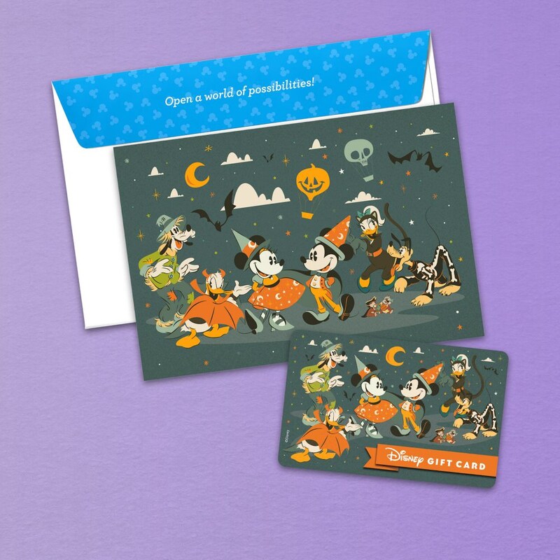 Una Tarjeta de Regalo Disney con temática de Halloween que incluye un diseño de Mickey Mouse y Minnie Mouse con disfraces de Halloween y el texto ‘Tarjeta de Regalo Disney’, junto a una tarjeta de nota a juego y un sobre