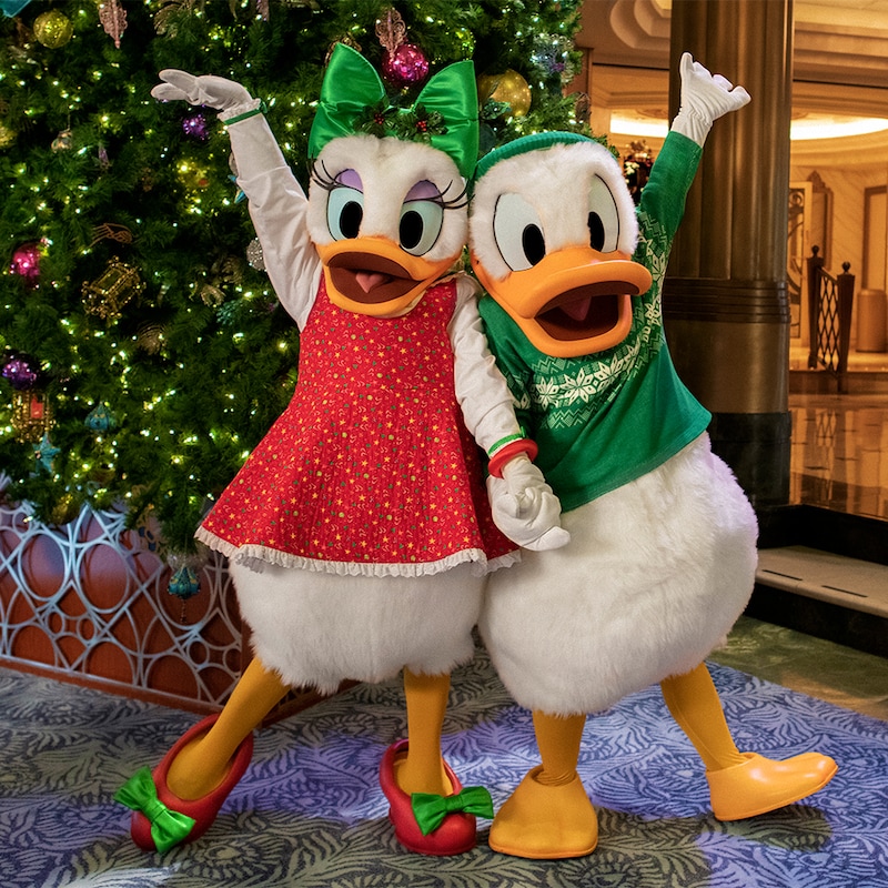 Donald Duck and Daisy Duck pose in front of a Christmas tree on a Disney Cruise Line ship